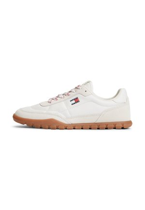 Biały niski sneaker z brązową gumową podeszwą, czerwono-białymi sznurowadłami i małym logo Tommy Hilfiger z boku.