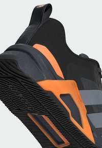 Musthave treeningkingad musta värviga, oranžide aktsentidega, tekstuurse tallaga, silmapaistva kannaosa ja triibulise disainiga. Omab tõmbenööri ja vastupidavaid materjale.