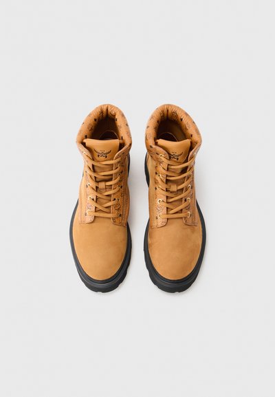 Tan suede boots with black rubber soles, round toe, padded collar, and lace-up front; interior features printed pattern.