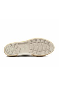 Suola della scarpa in beige chiaro con un motivo in gomma testurizzata, caratterizzata da scanalature per la trazione e un logo circolare al centro.
