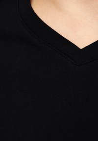 Sort V-hals T-shirt med et glat, strækbart stof, ribbet halsudskæring og ren syning langs kanterne. Minimalistisk designfokus.