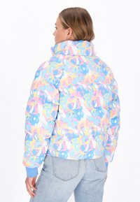 Prošívaná bunda s vícebarevným abstraktním vzorem v pastelových odstínech, která má vysoký límec, elastické manžety a zkrácený střih.