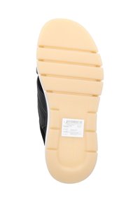 Baskets en cuir noir avec une tige texturée et une semelle en caoutchouc crème présentant des rainures horizontales pour une meilleure adhérence, et une étiquette avec les détails du produit.