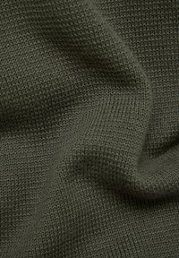 Dunkelolivgrüner gestrickter Stoff mit feiner Rippstruktur und sanften Falten, die sanfte Schatten erzeugen.