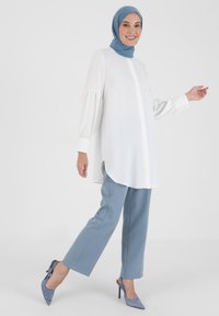 White long-sleeve blouse with balloon sleeves, paired with light blue straight-leg trousers and matching pointed heels, along with a blue hijab.