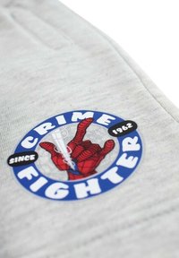 Tissu gris avec un graphisme circulaire bleu. Présente un geste de main rouge de Spider-Man et le texte « CRIME FIGHTER » et « SINCE 1962 » en blanc.