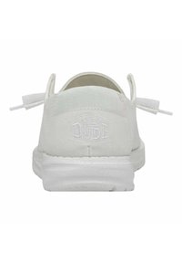 Scarpa slip-on bianca in canvas con superficie texturizzata, suola flessibile e logo ricamato "HEY DUDE" sul tallone, dotata di linguette in tessuto.