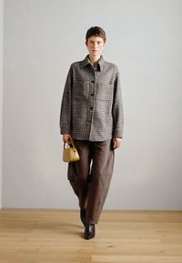 Auduma žakete ar pelēku pārbaudi, ar lieliem pogām, kombinēta ar brūniem platām biksēm un melniem augstpapēžu potīšu zābakiem. Mazs dzeltenais rokassomu.