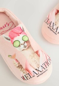 Pinke Hausschuhe mit einem Lama, das Gurken-Augenmasken trägt, einen rosa Handtuchturban auf dem Kopf hat, einen Cocktail hält und die Worte „ENTSPANNUNG und Verjüngung“ zeigt.