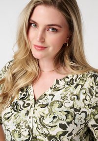 Bloemenbutton-up blouse in crème met groene en zwarte patronen, met korte mouwen, een v-hals en een gladde stofstructuur.