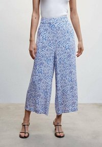 Siniset, kuviolliset culottes-housut, joissa on rento malli, nilkkapituus, hillitty paisley-kuviointi ja vyötärönauha. Yhdistetty mustiin remmisandaaleihin.