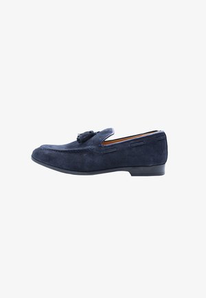 Mocassino da uomo in camoscio blu navy con nappine, tacco basso nero e dettagli cuciti, mostrato di profilo su sfondo bianco.