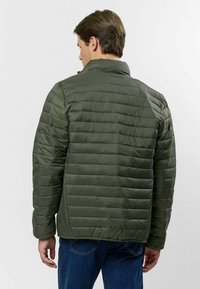 Tmavohnedá péřová bunda s prešívaným vzorom, vysokým golierom a hladkou textúrou. Pohľad zozadu zobrazuje voľný strih a polstrovanú štruktúru.