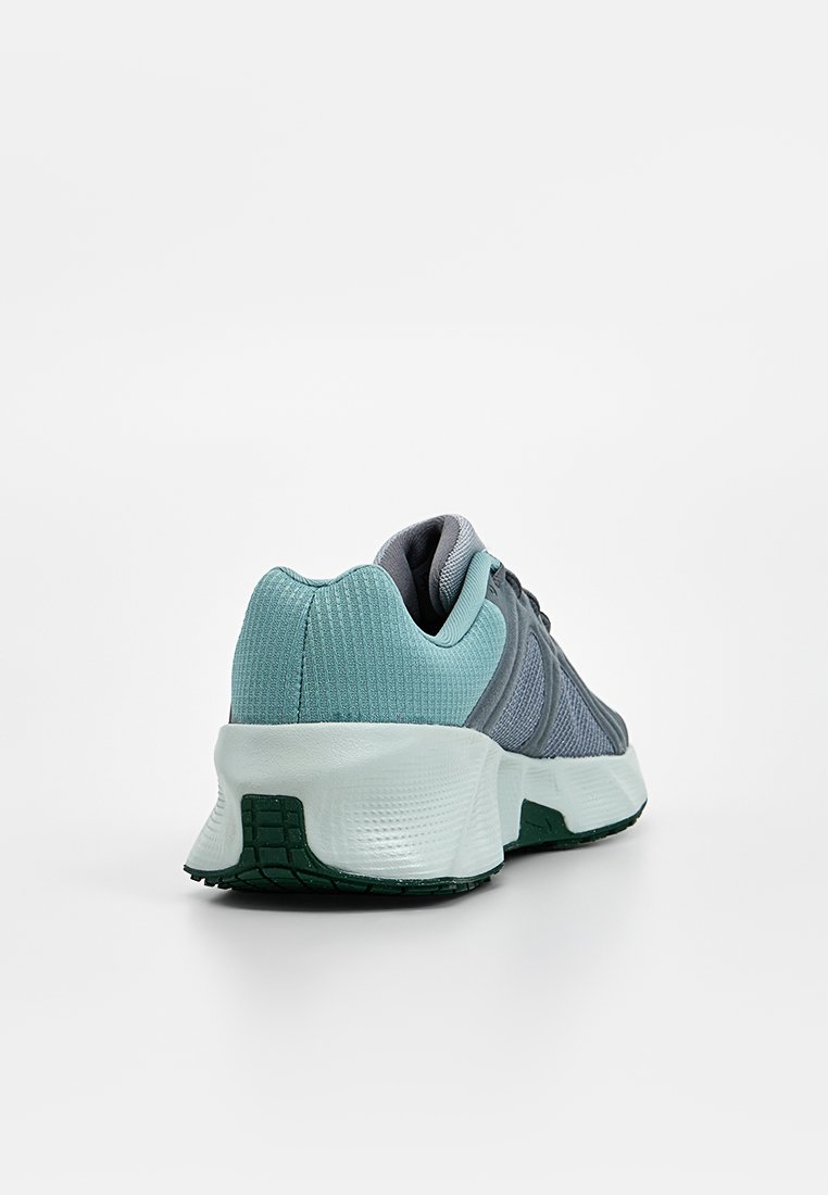 Zapatilla deportiva con parte superior de malla gris y detalles en verde azulado, cuello acolchado y suela blanca texturizada con patrón de color verde en la suela exterior.