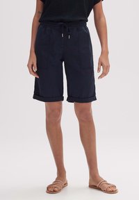 Granatowe szorty z wiązanym pasem, z podwiniętymi mankietami i dwoma przednimi kieszeniami. Wykonane z lekkiego materiału, odpowiednie do codziennego noszenia.