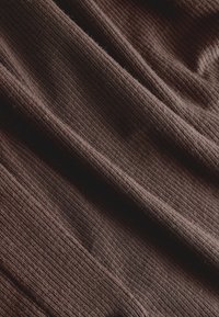 Tissu tricoté d'une riche couleur marron, présentant une texture côtelée verticale avec des fibres douces et fines et un drapé délicat.