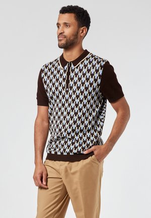 Suéter de polo de punto con un cuello marrón y mangas cortas, con un patrón geométrico azul y crema sobre una base oscura.