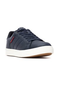 Chaussures en cuir synthétique bleu marine avec semelle en caoutchouc blanche, accents texturés, bout rond et lacets. Comprend une petite étiquette de marque rouge.
