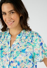 Bloemen blouse van een lichtgewicht stof, met korte mouwen, een knoopsluiting en een geplooide schouderpas in tinten blauw, roze en groen.