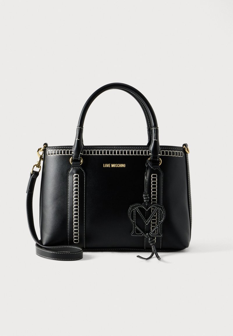 Μαύρη δερμάτινη τσάντα χειρός με αντιθετική λευκή ραφή, διπλές λαβές, αποσπώμενο ιμάντα ώμου και κρεμαστό ταμπελάκι με το λογότυπο "M".