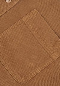 Tissu texturé brun avec une poche à rabat. Présente un design côtelé et une fermeture à boutons dissimulée. Matériau doux avec un léger éclat.