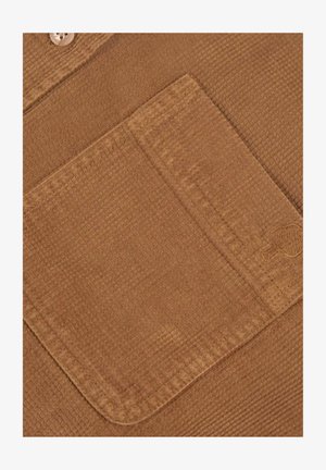 Bruine textuurstof met een opgestikte zak. Kenmerkt zich door een geribd ontwerp en verborgen knoopsluiting. Zacht materiaal met een subtiele glans.