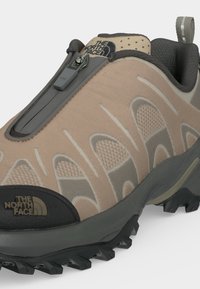 Μπεζ και γκρι πεζοπορικό παπούτσι North Face με υφασμένη σόλα, φερμουάρ στο πάνω μέρος και λογότυπα στη γλώσσα και στην πλευρά.