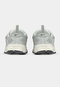 Graue Mesh-Sportschuhe mit einem strukturierten Muster, schwarzen Akzenten und einer weißen Sohle, die an der Rückseite einen Zugriemen und eine runde Form aufweisen.