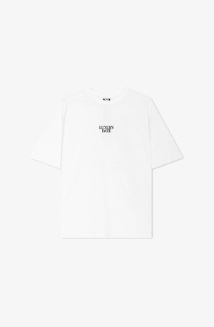 Camiseta blanca de algodón de corte relajado. Presenta el texto negro "LUXURY DATE" centrado en el pecho. Mangas cortas y cuello redondo.