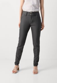Dark gray slim-fit trousers with a smooth texture, double-button closure, and tapered cuffs. Worn with beige strappy heeled sandals.