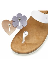 Witte sandaal met een zachte tan voetbed. Inclusief verwisselbare leren accessoires: een beige hart en een lavendelbloem met drukknoopsluiting.