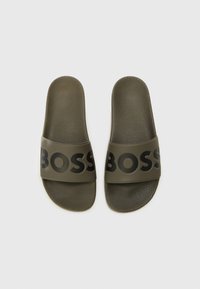 Olive green slide sandals with a textured footbed and a wide strap featuring the word "BOSS" in black. Smooth surface with a modern design.