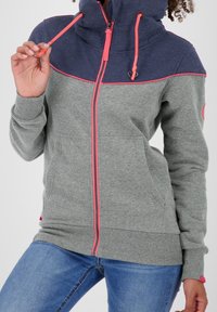 Felpa a zip grigia e blu navy con accenti rosa, caratterizzata da un collo alto, tasche frontali e polsini a coste. Texture morbida con colori a contrasto.