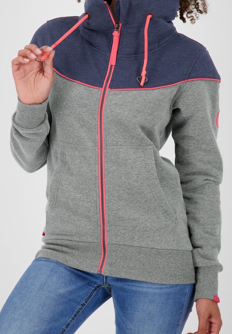 Felpa a zip grigia e blu navy con accenti rosa, caratterizzata da un collo alto, tasche frontali e polsini a coste. Texture morbida con colori a contrasto.