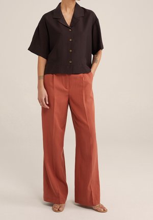 Black short-sleeve collar shirt with button front, paired with high-waisted, wide-leg rust-colored trousers. Simple design, lightweight fabric.