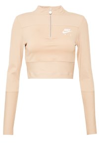 Ljusbeige långärmad cropped topp med hög krage och kvartzip. Har ribbad detaljering och en vit Nike Air-logotyp på bröstet.