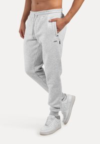 Grijze sweatpants van zachte stof met een elastische tailleband, zijzakken en geribbelde boorden, gecombineerd met witte sneakers.