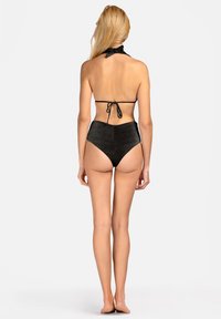 Czarny bikini z wysokim stanem i dekoltem halter; teksturowany materiał z delikatnym połyskiem; wiązania na szyi i plecach; minimalne zakrycie z tyłu.