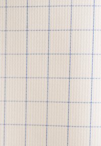 Tissu à motif en grille avec une surface texturée, composé d'un matériau beige clair et de fines coutures bleues délimitant les carrés.