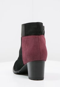 Stivale alla caviglia in suede nero e bordeaux con tacco robusto, caratterizzato da una tomaia liscia, sezioni a contrasto e una zip laterale.