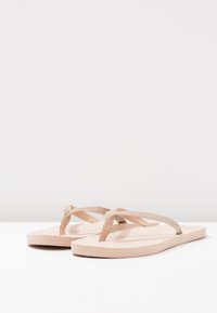 Sandalete roz deschis cu barete strălucitoare bej, talpă plată, design minimalist, material flexibil și fără modele sau accente vizibile.