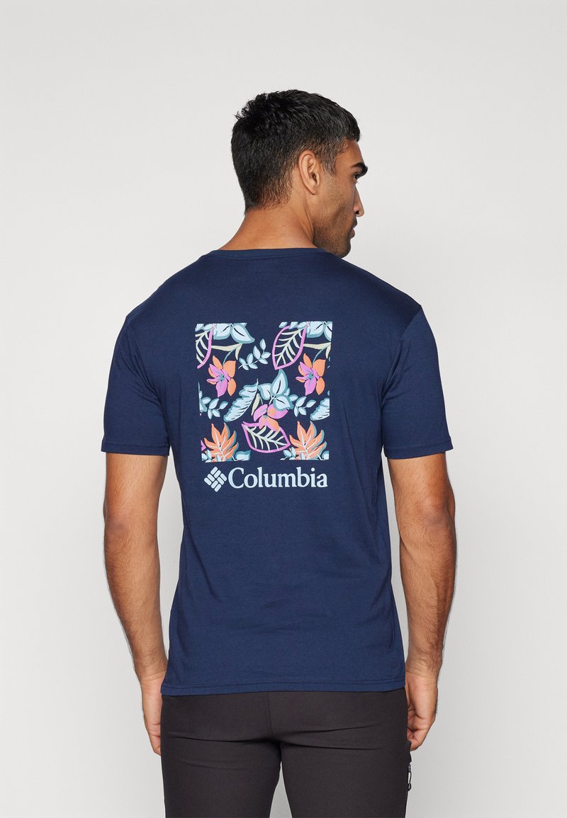Mørkeblå t-skjorte med korte ermer som har et fargerikt blomsterdesign på ryggen, med Columbia-logoen under designet.