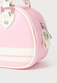 Roosa kunstnahast käekott valgete triipudega, ümar kuju, hõbedased detailid, südamekujulised aktsendid ja tõmbluku sulgemine.