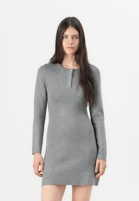 Robe en tricot grise à manches longues, col rond, et patte de boutonnage avec trois boutons au niveau du col. Texture lisse, design ajusté.