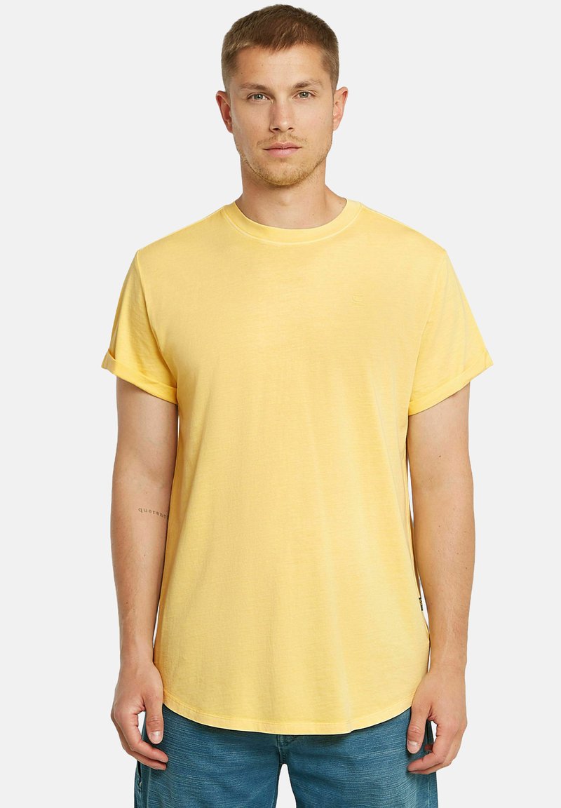 T-shirt giallo a maniche corte in tessuto leggero con scollatura rotonda e maniche arrotolate. Presenta un logo discreto sul davanti.