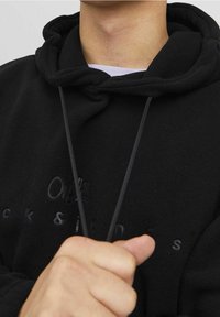 Zwarte fleece hoodie met een trekkoord, voorzien van een reliëflogo op de voorkant en een zachte, gemetste stof.