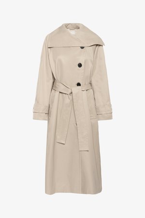 Bēšs tranča mētelis ar platu apkakli, trim melniem pogām, jostasvietas jostu, garām piedurknēm ar aproču siksnām un priekšējām kabatām.