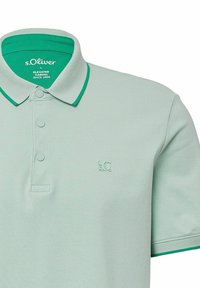 Hellgrünes Polohemd aus strukturiertem Stoff, mit kontrastierendem grünen Kragen, drei Knöpfen und einem kleinen Logo auf der Brust.
