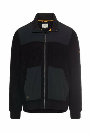 Schwarze Zip-Jacke mit gerippter Textur, einfarbigen Paneelen, zwei Fronttaschen und einem hohen Kragen. Innen mit einem kontrastierenden orangefarbenen Futter ausgestattet.