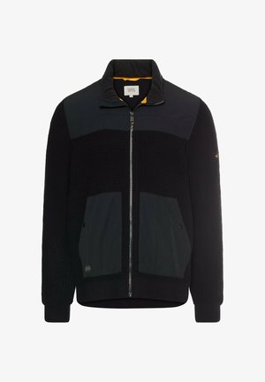 Czarna kurtka zapinana na zamek błyskawiczny z prążkowaną teksturą, gładkimi panelami, dwoma przednimi kieszeniami i wysokim kołnierzem. Posiada kontrastową pomarańczową podszewkę wewnątrz.